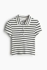 Remera polo de manga corta con cuello clásico y tapeta de botones. Diseño a rayas horizontales en blanco y negro, de corte entallado y tejido acanalado.