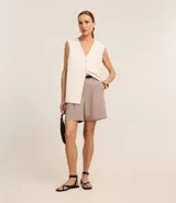 Short color visón de corte sastrero, tiro alto, con pliegues delanteros, trabillas y cinturón fino de cuero sintético.