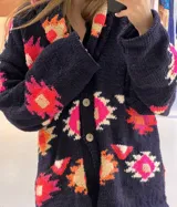 Saco de lana marrón con diseño geométrico multicolor, cuello con solapa, cierre frontal con botones y bolsillos delanteros.