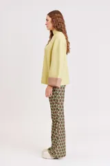 Pantalón acampanado con estampado geométrico en tonos marrón, verde oliva y verde claro.