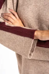 Sweater de punto azul marino con calce oversize. Presenta un detalle de franja vertical color marrón en la parte exterior de ambas mangas y un ribete fino dorado en el escote redondo.