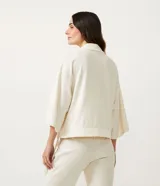 Kimono corto color crudo, con mangas 3/4 anchas y detalle en el bajo.