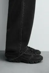 Zapatillas deportivas color crema con cordones, suela gruesa con diseño irregular y detalles en gris.