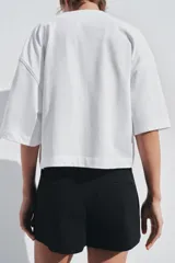 Camiseta blanca de algodón, corte oversize, cuello redondo, manga corta y detalle de aplique metálico con logo ZA en el frente.