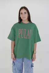 Remera verde con estampado de la palabra "Pulau" en color lila.