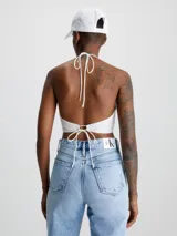 Blusa blanca con textura arrugada, escote halter y cierre anudado en la espalda.