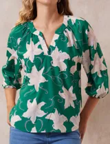 Blusa de gasa estampada marca Sioni, color verde con estampado floral blanco y celeste. Cuello a la base con escote en V y mangas 3/4 fruncidas.