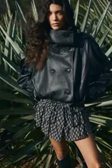 Minifalda negra con estampado floral blanco, cintura alta con elástico en la parte posterior y volados escalonados.