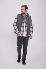 Chaleco puffer gris sin mangas con cuello alto y cierre de cremallera.