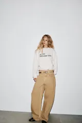 Sudadera corta color blanco hueso, de cuello redondo y manga larga. Tiene un estampado con la frase 'IN MY YEEHAW ERA' en color negro.