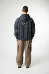 Hoodie color crema o blanco roto, de corte holgado y manga larga, con bolsillo canguro frontal y un pequeño logo bordado en el pecho.