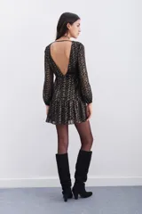 Vestido corto negro con estampado abstracto dorado, escote redondo, mangas largas con elástico en los puños, detalle de nudo drapeado en la cintura y escote en V pronunciado en la espalda.