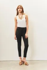 Pantalón de jean negro de corte skinny y tiro alto, confeccionado en gabardina con elastano y recubrimiento que simula cuero.