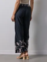 Pantalón negro con estampado de hojas color rosa en el ruedo y cintura elastizada con lazo ajustable.