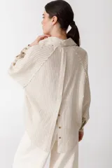 Camisa blanca de lino con botones de madera, corte recto y mangas largas.