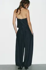 Pantalón bombacho de denim azul oscuro, tiro medio, con bolsillos laterales ocultos y de parche en la espalda. Presenta pinzas en la parte delantera y bajo abullonado con elástico.