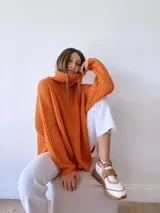 Zapatillas deportivas blancas con detalles en cuero color salmón y suela gruesa con detalles en naranja.