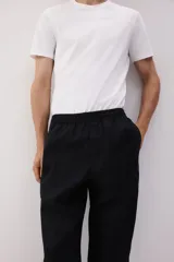 Pantalón negro de lino con corte recto, cintura elastizada con cordón ajustable, bolsillos laterales y bolsillo trasero.