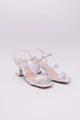 Sandalias de ecocuero charolado color negro, con punta cuadrada, dos tiras horizontales sobre el empeine, pulsera con hebilla al tobillo y taco cuadrado.