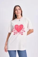 Remera de manga corta, corte oversize y cuello redondo, color crudo con estampado de corazón rojo y rosas.