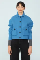 Chaqueta azul con cuello de corderito desmontable, botones metálicos y bolsillos delanteros.