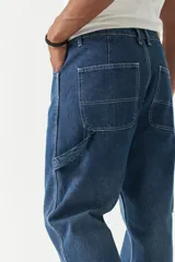 Pantalón jean celeste de corte amplio, estilo carpenter, con bolsillos laterales y logo bordado.