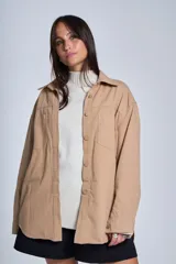 Sobrecamisa negra de gabardina con cuello camisero, cierre frontal con botones, mangas largas con puños abotonados y bolsillos de parche en el pecho.