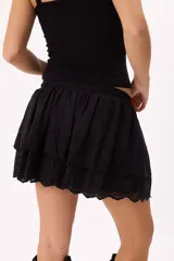 Minifalda color crema con bordado calado tipo broderie, cintura elastizada con cordón ajustable y detalle de cuentas de madera. Diseño de doble capa con volados.