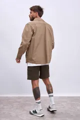 Cazadora color beige con cuello clásico, cierre frontal con botones, mangas largas y bolsillos de parche en el pecho.