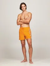 Short de baño naranja con estampado de monogramas TH en blanco a lo largo de la pierna.