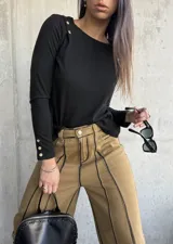 Remera negra de manga larga con cuello redondo y botones decorativos en el hombro y los puños.