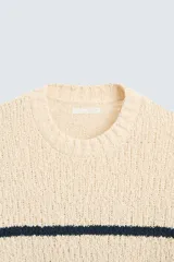 Sweater de punto color crema con rayas horizontales azul marino, cuello redondo y manga larga.