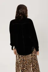 Camisa negra de terciopelo con corte estilo jean, bolsillo en la parte delantera y botones símil metal color oro viejo.