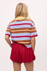 Remera tejida con rayas horizontales marrones, rosas y turquesas, cuello polo y calce boxy.