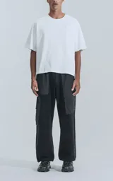 Pantalón tipo jogger negro, de calce relajado, confeccionado en algodón y microfibra. Presenta paneles de microfibra en la parte superior y bolsillos cargo con fuelle en las piernas. Los tobillos son ajustables con cordón elástico.