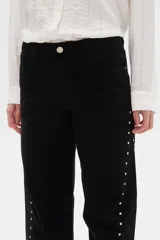 Pantalón jean negro de tiro alto, corte flare y detalle de tachas plateadas en los laterales.