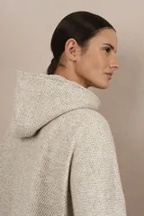 Capa color crudo de lana fina sin teñir, con capucha, cierre frontal y bolsillos con cierre.