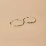 Par de aros tipo argolla de plata 925, con diseño torneado y detalles de alambre de oro enrollado en la unión.