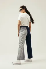 Pantalón de jean de pierna ancha con diseño color block: una pierna azul oscuro y otra gris claro.