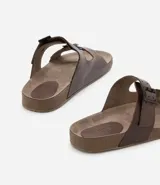 Sandalias tipo slide de cuero color marrón con dos tiras anchas ajustables con hebillas metálicas. Suela plana con textura. Marca Viko.