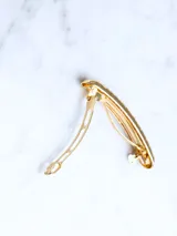 Broche dorado para el cabello con diseño texturizado.