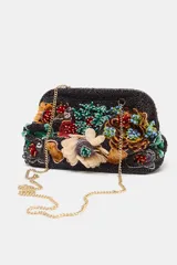 Bolso de mano con cuerpo en abalorios negros y diseño floral multicolor. Tiene asa de anillas metálicas extraíble en forma de bandolera, bolsillo interior y forro interior. Cierre mediante clip.