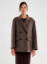 Chaqueta de lana con textura afelpada, color marrón jaspeado. Diseño cruzado con doble botonadura de botones oscuros, solapa clásica y bolsillos con tapa. Corte recto y ligeramente oversize.