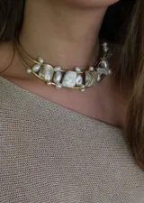 Gargantilla rígida dorada con doble aro y apliques de perlas irregulares y piezas de nácar.