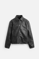 Cazadora cropped fit confeccionada en tejido efecto piel color negro. Tiene cuello solapa, manga larga con puño abotonado, bolsillos de vivo en cadera, bolsillo interior y cierre frontal con botones a presión.