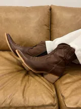 Bota texana corta color chocolate, de cuero, con punta fina y bordados decorativos en el empeine.