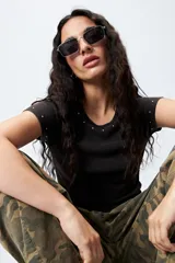 Remera blanca de punto acanalado con cuello redondo y mangas cortas. Presenta apliques de strass en el escote y las mangas.