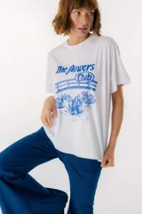 Remera blanca de algodón con estampado de tres jarrones con flores rojas y la frase "The Flowers Club" en azul.