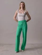 Pantalón naranja de crepe elastizado, corte recto, con bolsillos delanteros y apliques de botones metálicos.
