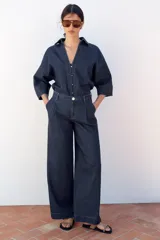 Pantalón de jean azul oscuro, corte wide leg, tiro alto con pinzas delanteras, bolsillos laterales y cierre frontal con cremallera y botón.